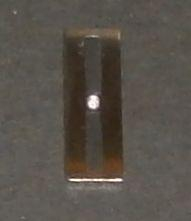 Ocelová destička se světlým kamínkem uprostřed a dvěma černými pruhy